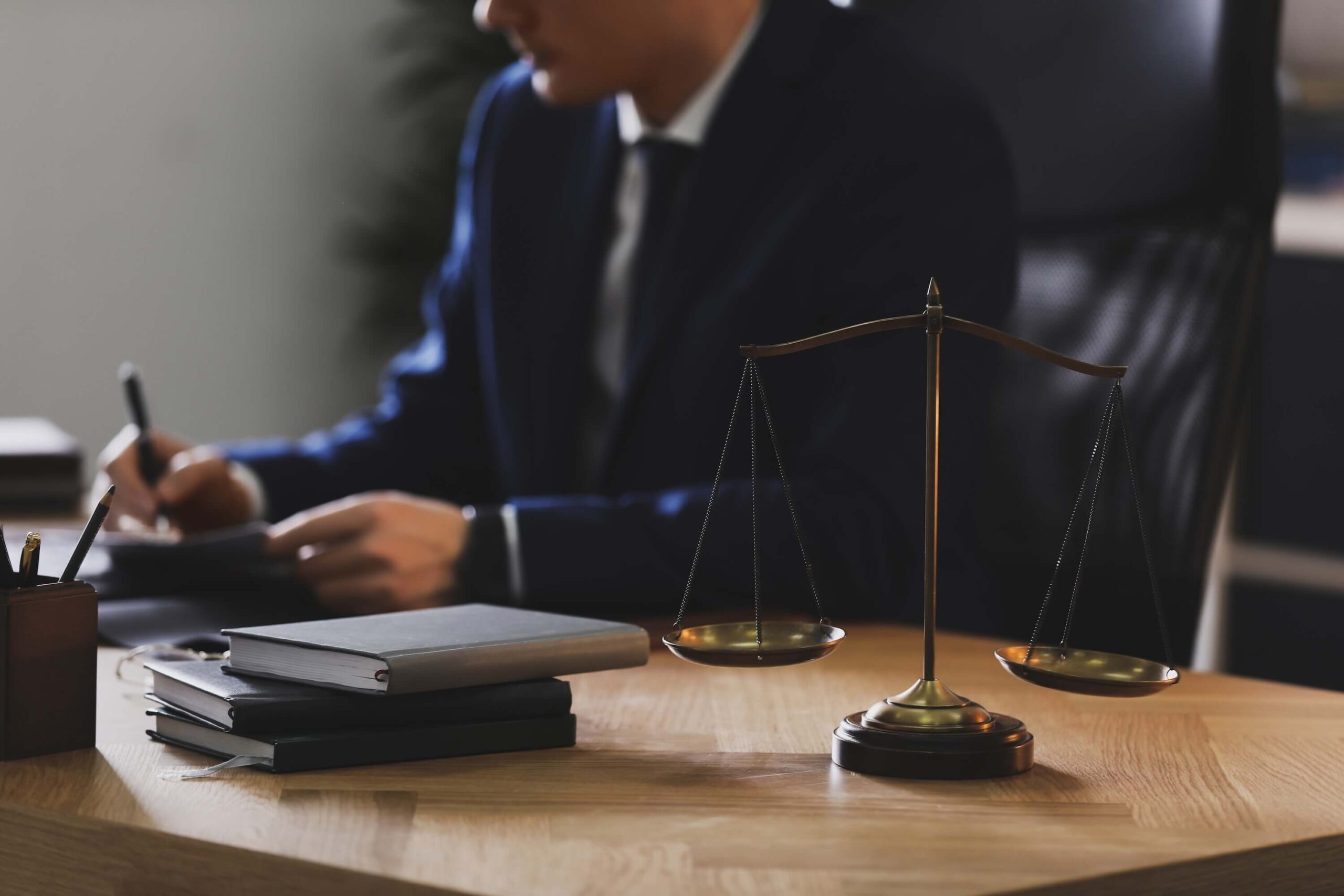 Male lawyer working at table in office, focused on scales of justice
