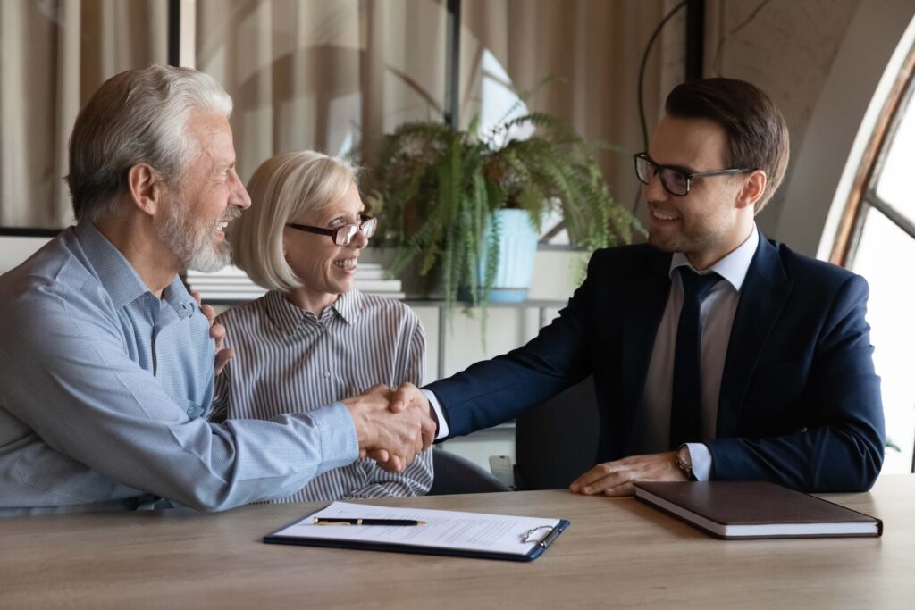 Happy older married couple shaking hands with an agent, notary